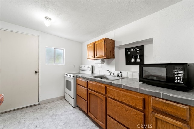 kitchen featuring a textured ceiling, electric stove, tile counters, light tile patterned floors, and sink