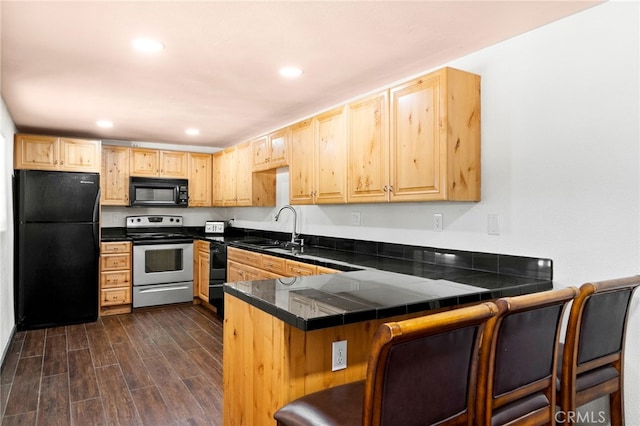 kitchen featuring dark hardwood / wood-style floors, a kitchen breakfast bar, sink, black appliances, and kitchen peninsula