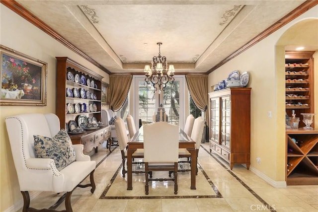 dining area with crown molding, a tray ceiling, plenty of natural light, and an inviting chandelier