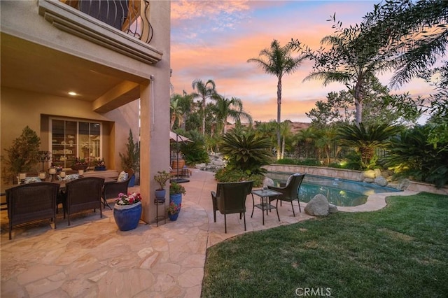 patio terrace at dusk featuring a yard