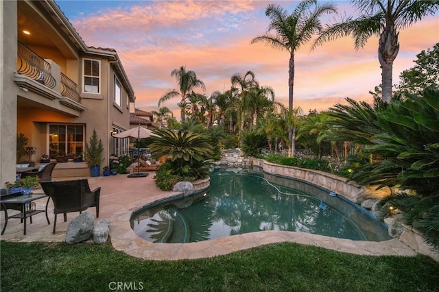 pool at dusk with a patio area