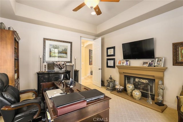 carpeted office featuring ceiling fan and a raised ceiling