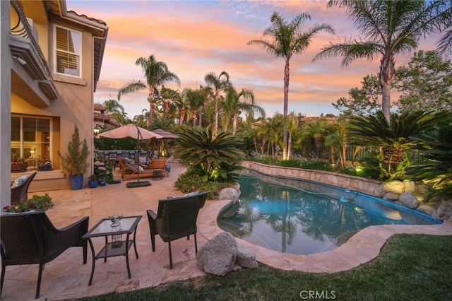 pool at dusk featuring a patio