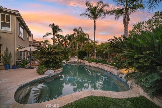 pool at dusk featuring a patio area