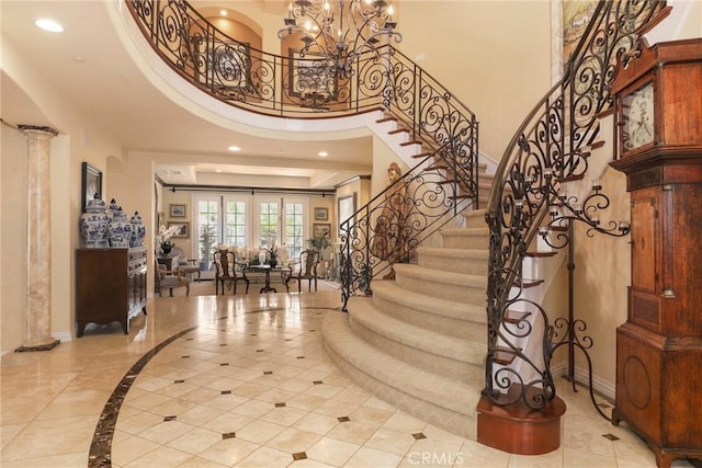 entryway featuring decorative columns, a high ceiling, and a notable chandelier