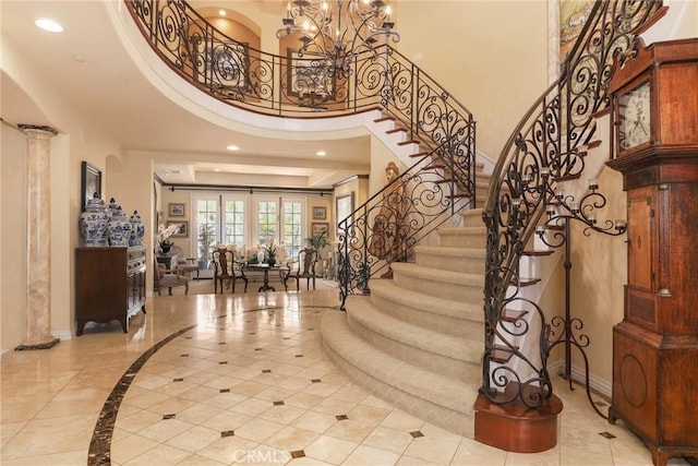 entryway featuring an inviting chandelier, a towering ceiling, and ornate columns