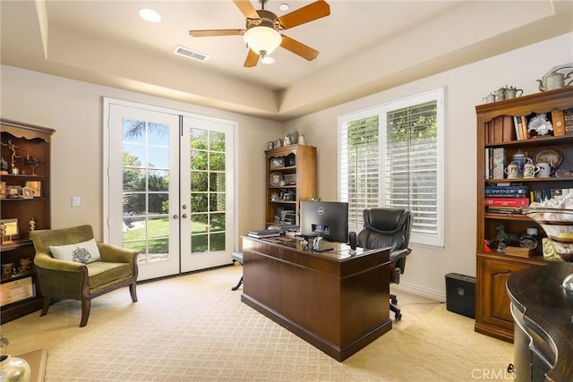 office space featuring light colored carpet, a raised ceiling, and french doors