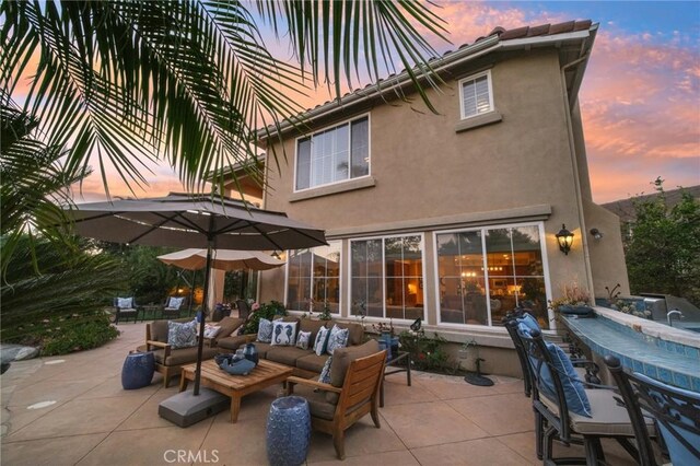 back house at dusk featuring a patio and an outdoor hangout area