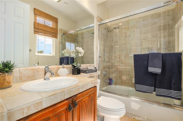 full bathroom with enclosed tub / shower combo, vanity, and toilet