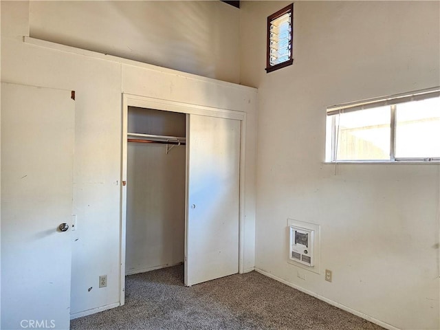 unfurnished bedroom featuring carpet flooring, heating unit, and a closet