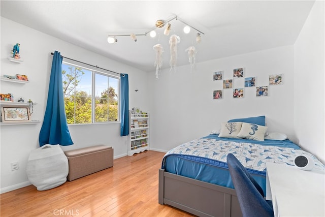 bedroom with light wood-type flooring, rail lighting, and an inviting chandelier