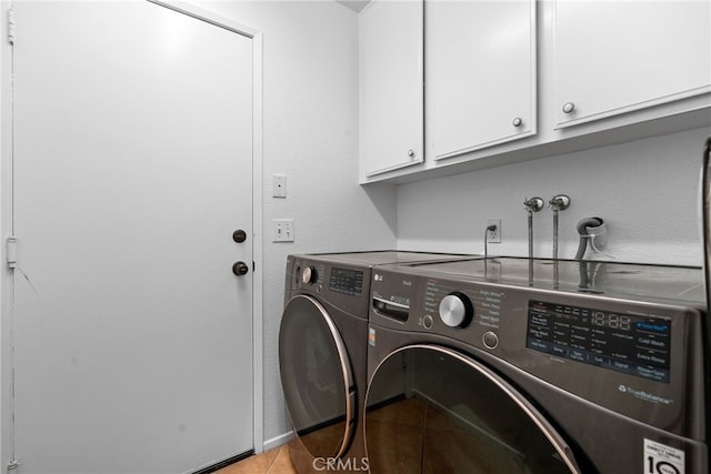 laundry area with cabinets, light tile patterned floors, and washer and clothes dryer