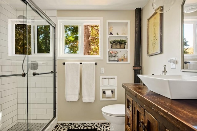 bathroom featuring an enclosed shower, vanity, toilet, and a wealth of natural light