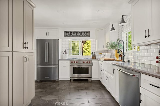 kitchen featuring premium appliances, white cabinetry, decorative backsplash, and sink