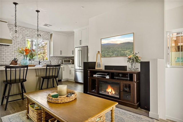 kitchen featuring white cabinetry, hanging light fixtures, dark hardwood / wood-style floors, a breakfast bar area, and high end fridge