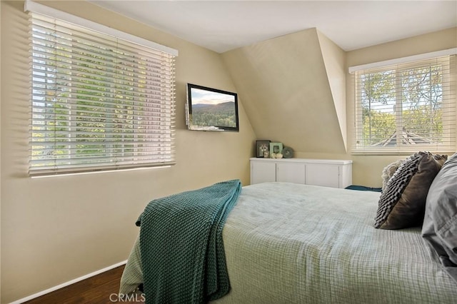 bedroom featuring vaulted ceiling, dark wood-type flooring, and multiple windows