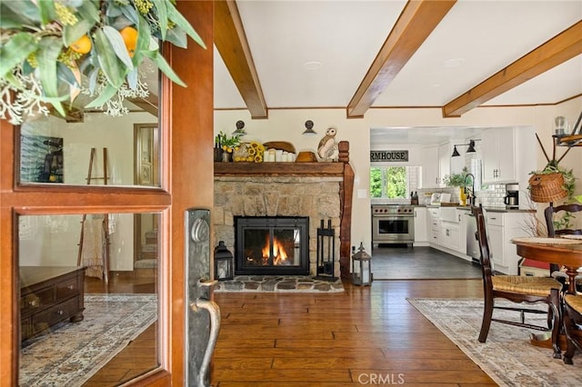 living room with beamed ceiling, a fireplace, sink, and dark wood-type flooring