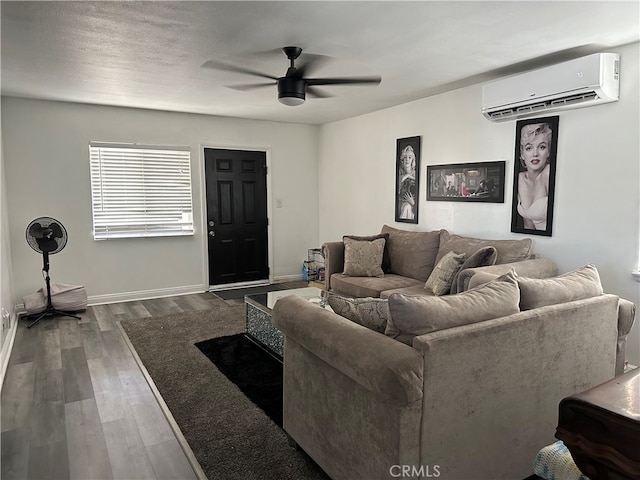 living room with ceiling fan, wood-type flooring, and a wall unit AC