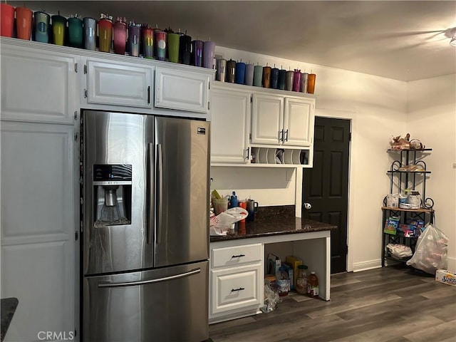 kitchen featuring stainless steel fridge, dark stone counters, and white cabinets