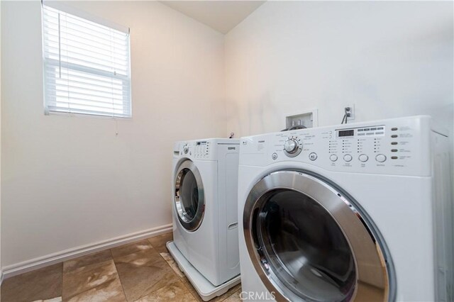 clothes washing area featuring dark tile patterned floors and washing machine and clothes dryer