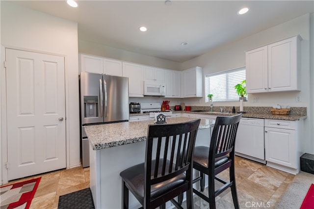 kitchen featuring light tile patterned floors, light stone counters, white appliances, and a kitchen island