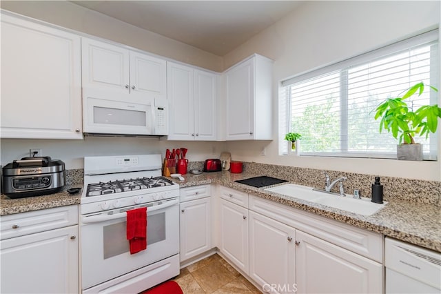 kitchen featuring white appliances, light tile patterned flooring, light stone countertops, sink, and white cabinets