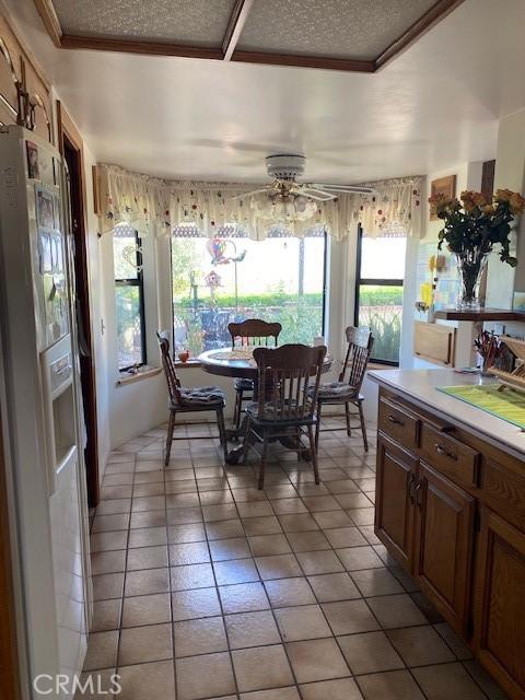 dining room featuring ceiling fan, light tile patterned floors, a textured ceiling, and ornamental molding