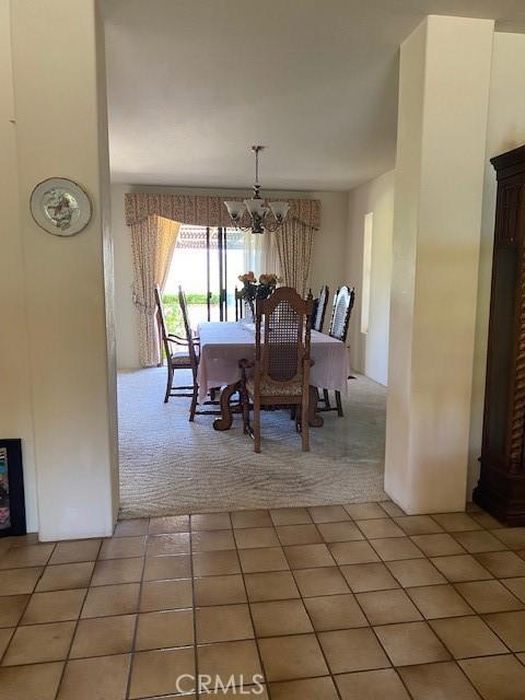 dining room with tile patterned floors and an inviting chandelier