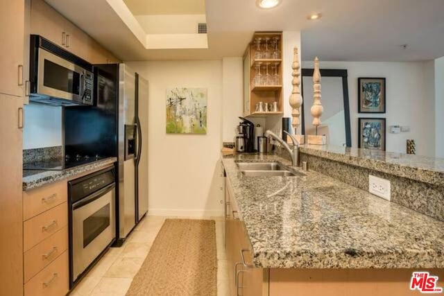 kitchen featuring light tile patterned flooring, stainless steel appliances, light stone countertops, sink, and kitchen peninsula