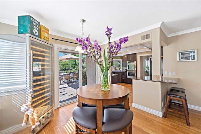 dining room featuring light hardwood / wood-style flooring, beverage cooler, and ornamental molding