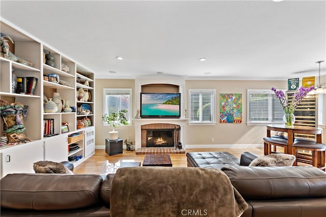 living room featuring light hardwood / wood-style flooring, a fireplace, and crown molding