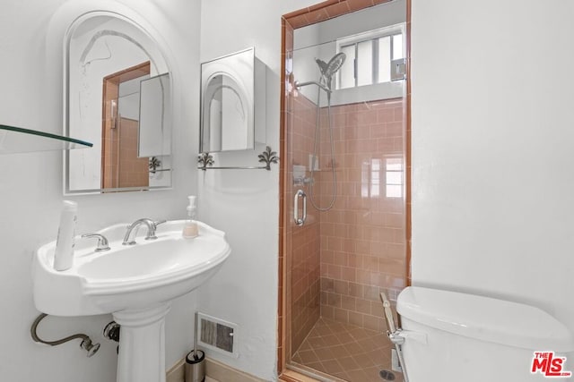 bathroom featuring toilet and a shower with door