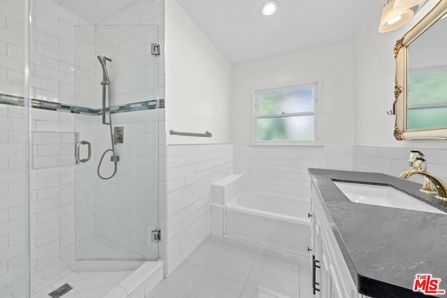 bathroom featuring tile patterned floors, independent shower and bath, vanity, and tile walls