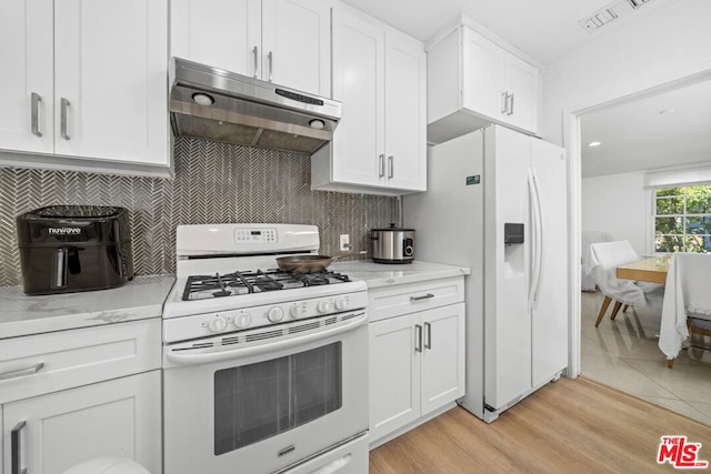 kitchen featuring light wood-type flooring, light stone countertops, white appliances, and white cabinets