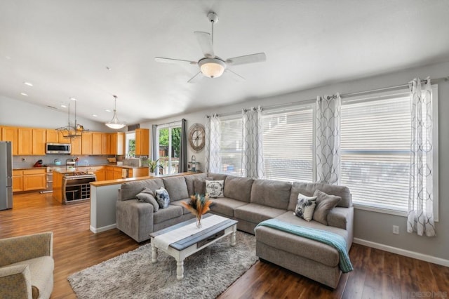 living room with vaulted ceiling, ceiling fan, a wealth of natural light, and dark hardwood / wood-style floors