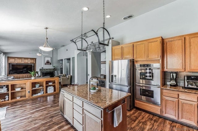 kitchen featuring stainless steel appliances, dark stone countertops, vaulted ceiling, pendant lighting, and a center island