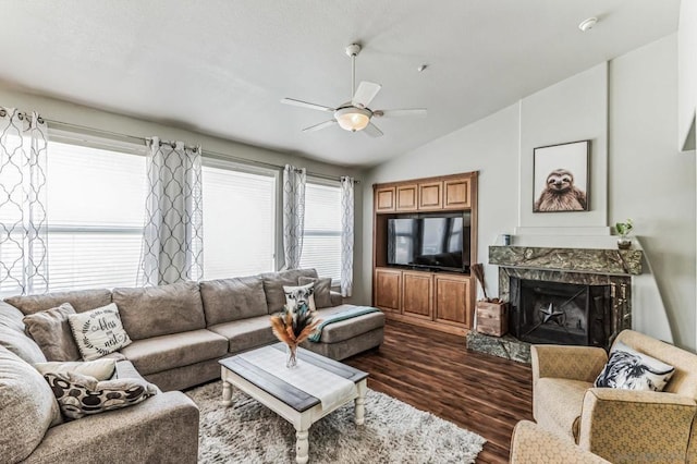 living room with ceiling fan, dark hardwood / wood-style flooring, a premium fireplace, and vaulted ceiling