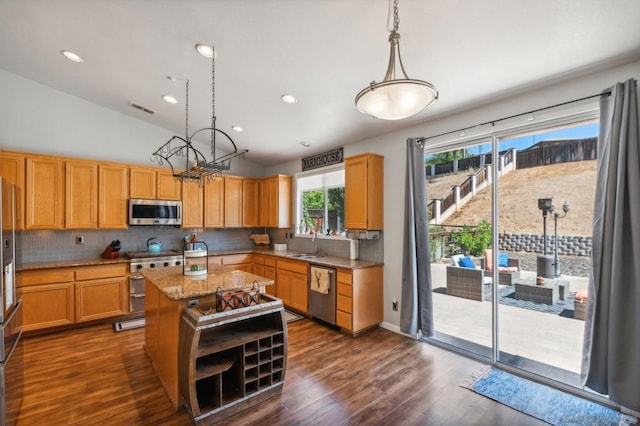 kitchen featuring appliances with stainless steel finishes, vaulted ceiling, a kitchen island, pendant lighting, and sink