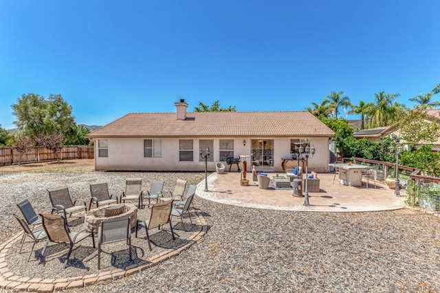 back of house with an outdoor fire pit and a patio