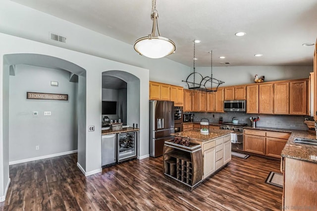 kitchen featuring beverage cooler, a kitchen island, decorative light fixtures, stainless steel appliances, and decorative backsplash