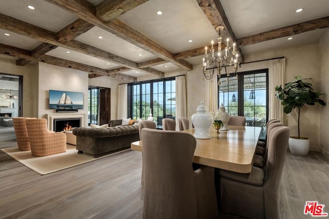 dining area featuring beam ceiling, light wood-type flooring, a chandelier, and a wealth of natural light