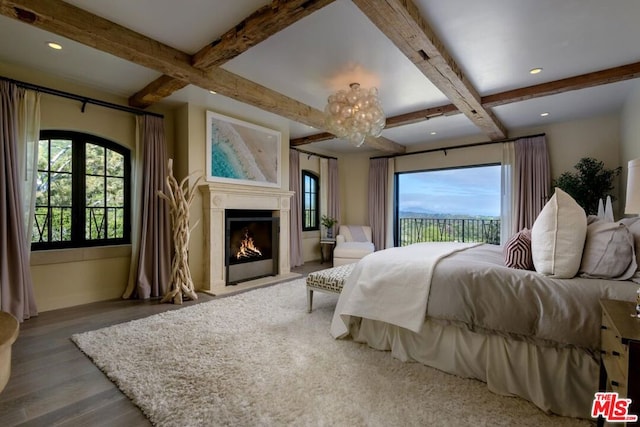 bedroom featuring beam ceiling, light wood-type flooring, and multiple windows