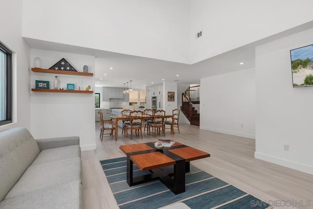 living room with light hardwood / wood-style floors, a high ceiling, and a wealth of natural light