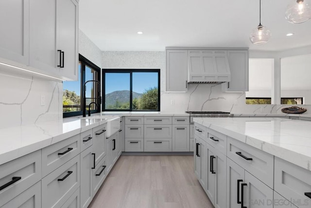 kitchen with light stone counters, pendant lighting, decorative backsplash, and a mountain view