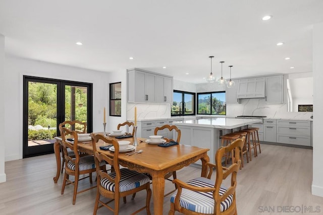 dining room featuring french doors, a wealth of natural light, light hardwood / wood-style flooring, and sink