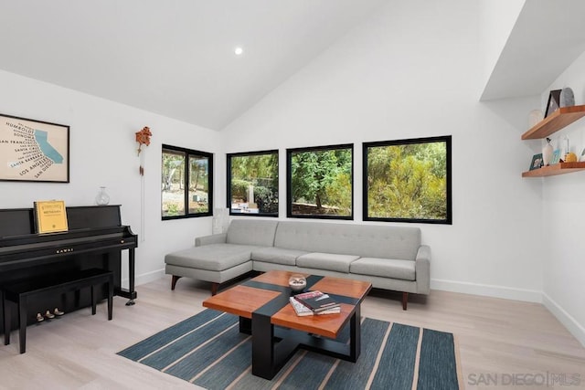 living room featuring high vaulted ceiling, light hardwood / wood-style flooring, and a healthy amount of sunlight