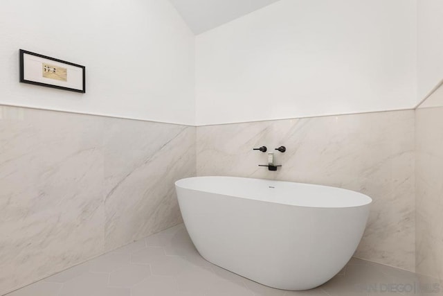 bathroom with a washtub, tile walls, and tile patterned flooring