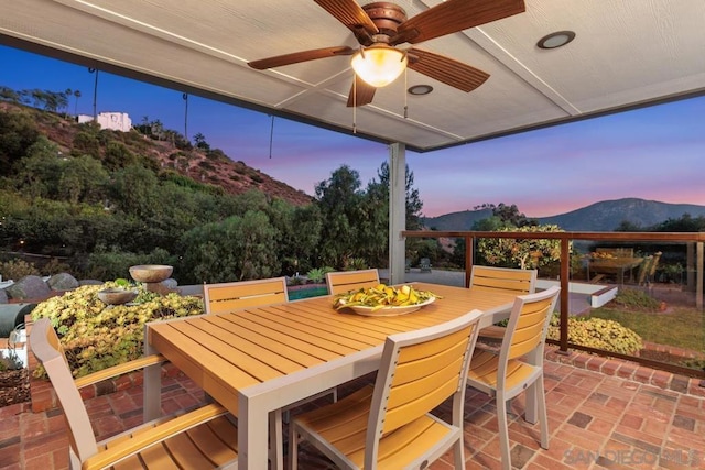 patio terrace at dusk featuring ceiling fan and a mountain view