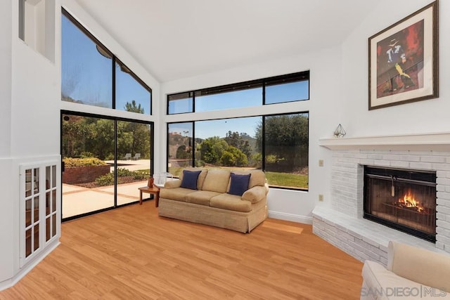 living room featuring a fireplace, a towering ceiling, and light hardwood / wood-style flooring