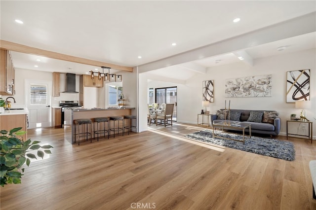 living room featuring sink, wood-type flooring, beamed ceiling, and a healthy amount of sunlight